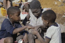 Three children eating from rubbish dump.township