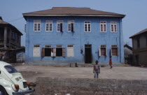 Blue painted exterior of typical house with wooden shutters and children in yard outside.