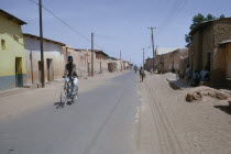 Street scene in old city with cyclist on road lined with mud brick architecture.   bike bicycle
