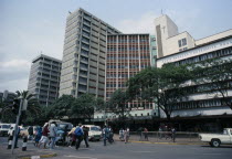 Downtown Nairobi with people crossing road  waiting traffic and high rise buildings.