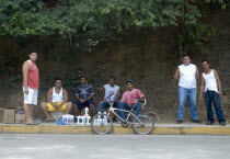 Group of youngsters selling engine oil by the side of the street.