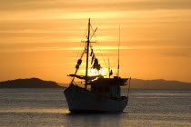 Sun setting over a fishing boat in Juan Griego port.