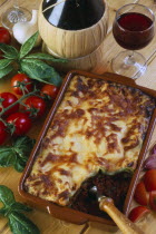 Lasagne in serving dish with basil  tomatoes and red wine.