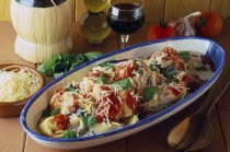 Tortelloni in tomato and wild mushroom sauce in serving dish displayed with basil  tomatoes garlic and red winepasta