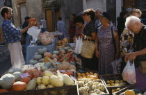 Man with customers selling gourds at weekly market stallVegetables