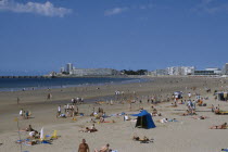 Twinned with Worthing. View over busy sandy beach to atlantic coastline