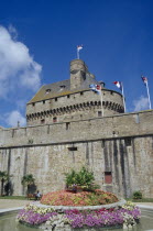 St. Malo.  Chateau Gaillard  exterior with flags flying from crenellated wall and water feature with central flowerbed in the foreground.