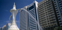 Al-Ittihad Square. Fountain of water falling from the spout of a sculpted Arabian coffeepot or dallah with high rise buildings behind. United Arab Emirates