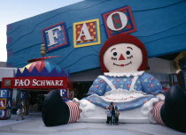 International Drive. Pointe Orlando Shopping Area. FAO Schwarz Toy store chain exterior with a family having their photograph taken next to a giant Raggedy Ann statue