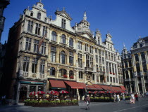 Highly decorated buildings in the historic square with outdoor restaurants and umbrellas.