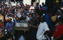 Mixed crowd listening to sound system DJ and crew at the Notting Hill Carnival.