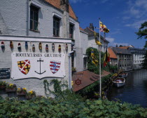 Boat house with a sign for excursions  Different countries flags painted onto clogs. Boats docked on the canal  and flags flying.