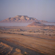 Nr Ruwais  Desert and hills with vehicle tracks on flat area in foreground seen on a Misty morning  United Arab Emirates