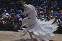 Crop Over festival celebrating the sugar cane harvest with reveller dressed in horse costume parading in front of crops.