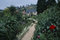 A path leading through Claude Monet s garden towards a house.