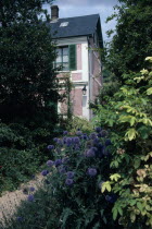 Giverny. Claude Monet s house with shuttered windows seen through garden foliage.