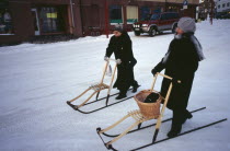 Female shoppers in snow using single sleds.  Winter