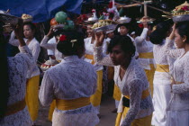 Procession of women carrying food offerings to temple on occasion of temple birthday festival.