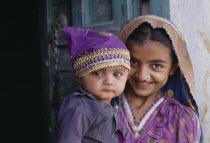 Dhordo Village.  Girl with nose ring holding young child.