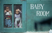 Young Tibetan refugee children looking out from inside creche.