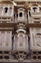 Detail of intricately carved facade of sandstone merchant s house or Haveli with pigeons roosting on the overhanging ledges.