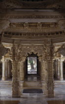 Dilwara Temple complex dating from 11th-13th century A.D.  Detail of intricately carved white marble ceiling and supporting pillars framing view to outside courtyard.
