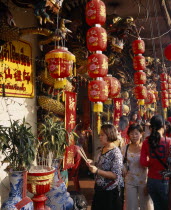 Wat Traimit.  People offering prayers and incense at temple decorated with red Chinese lanterns and strings of coloured lights for Chinese New Year.Colored