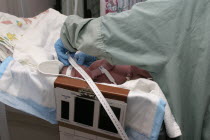 Nurse taking newborn baby measurements in hospital