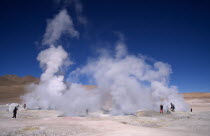 Tourists amongst steam rising from geothermal geysers.