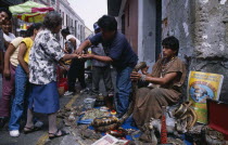 Shaman selling snake grease and other  cures  for ailments on city street with stall laid out with snake skins  reptile parts etc.