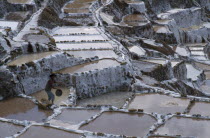 Man working on salt terraces near Maras used to collect salt by evaporation since Inca times. Cuzco