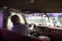 Passenger seat view of a Caracas taxi including ventilation fan and dash-board ornaments
