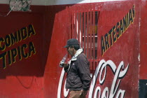 Man drinking a soft drink next to a Coca Cola advert  Apartaderos village  Venezuelan Andes  Close to Merida