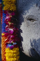 Flower garland offering hanging over stone elephant statue.