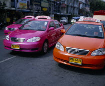 Pink and orange taxi cabs on busy road.