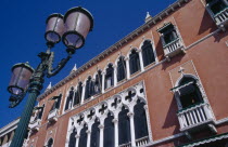 Terracotta and white painted facade of the Danieli Hotel with street lamp in foreground.