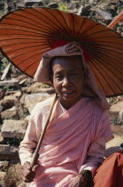 Portrait of nun wearing traditional pink robes holding locally made parasol.Dasasila or ten precept nuns sometimes called thilashin Burma Myanmar