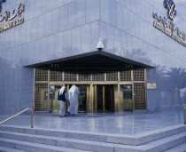 Exterior of Al-Ahli Bank of Kuwait with two men about to enter.