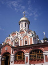 Part view of exterior of refurbished church with red and white painted facade  gold domed roof and painted icons above the entrance.Eastern Europe