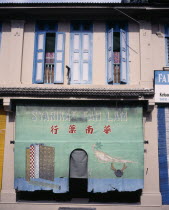 Jalan Temenggong.  Building exterior with painted shade hanging over entrance and open blue and white painted shutters above.