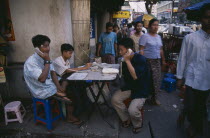 Public telephone exchange.  Young men using telephones set up on folding table on busy street.Burma Rangoon