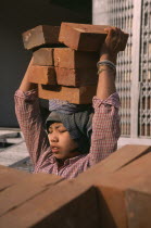 Female construction worker carrying bricks on her head.Burma Myanmar