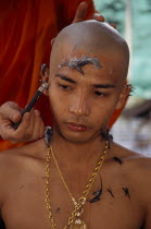 Novice monk having head shaved during ordination ceremony.