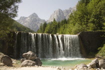 A waterfall on Velika Pisnica with Mounts Razor and Prisank in the Julian Alps in the background. There is still snow lying on the mountain after a severe winter  Clear blue waterclean water import...