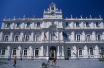 Classical architecture of the Gymnasium exterior with people on bicycles in the foreground