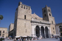 Monreale. II Duomo Norman Cathedral exterior with people gathered around small market stalls next to the walls