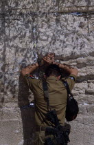 An Israeli Soldier in army uniform with a M16 Assault Riffle around his shoulder praying at The Western WallAlso known as The Wailing Wall