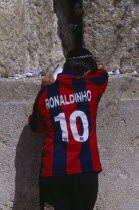 An Israeli boy wearing a Ronaldinho football shirt praying at the Western Wall. Also known as The Wailing Wall