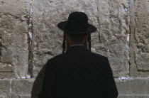 An Ultra Orthodox Jewish Man wearing a black hat and coat praying at the Western WallAlso known as The Wailing Wall