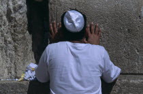 A Jewish man wearing a white Kippah praying at the Western WallAlso known as The Wailing Wall